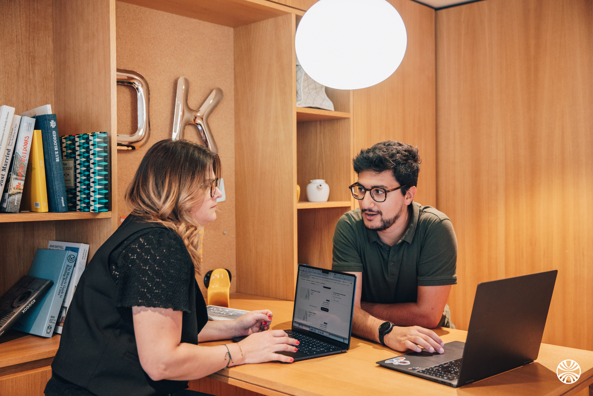 Deux professionnels collaborant sur leurs ordinateurs portables dans un bureau moderne.